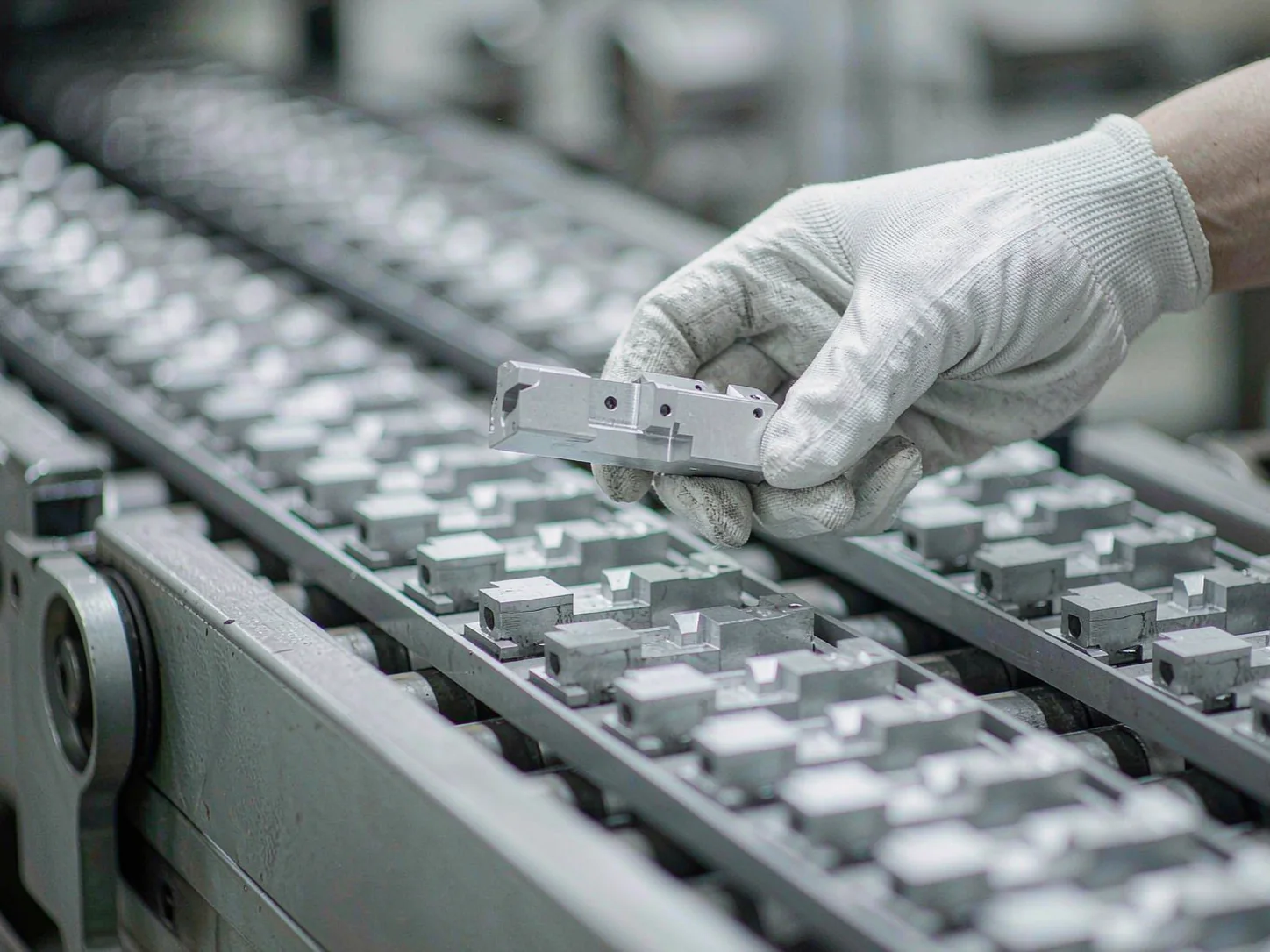 Hands in white gloves sampling parts from a production tray