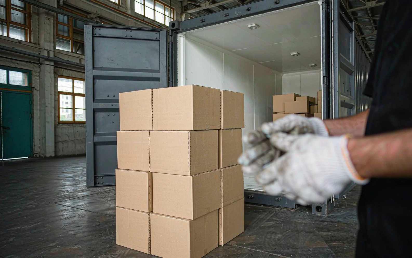 Hands in white gloves sealing a packed carton