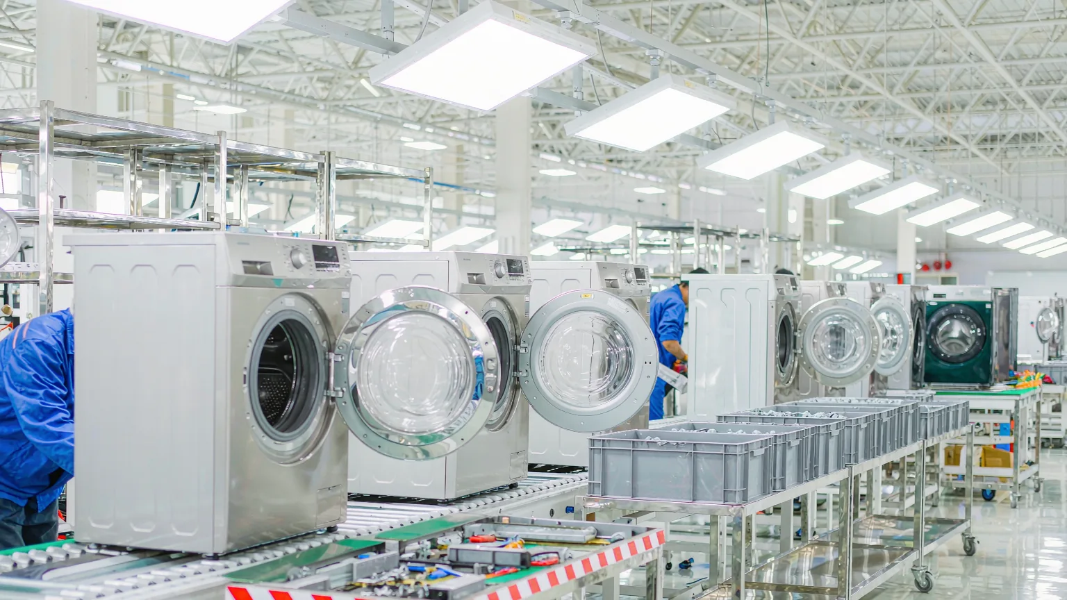 Washing machines moving along the assembly line inside a home appliance factory while mass production is still running