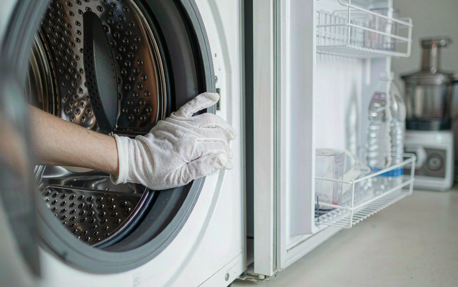 Hands in white gloves checking the interior of a washing machine