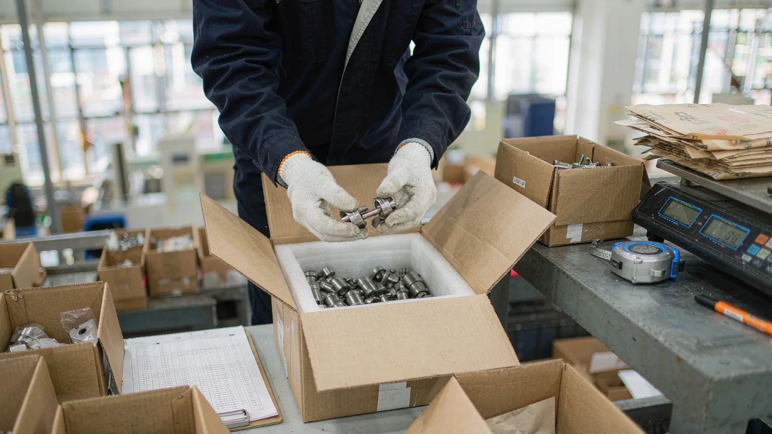 Machined steel parts counted and packed into a foam-lined export carton before the balance payment