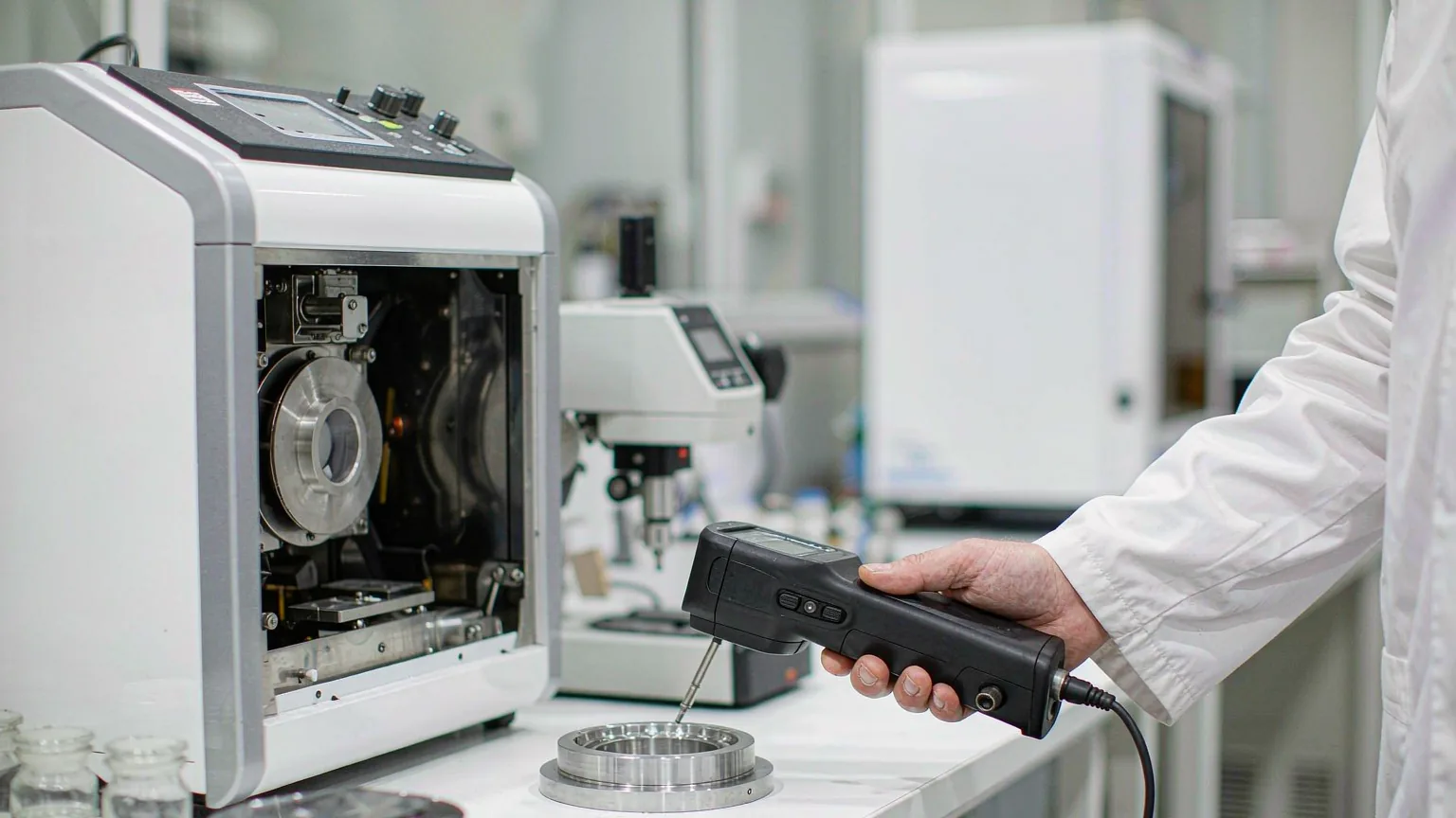 Laboratory testing of machined parts — handheld XRF alloy reading and coupons prepared for salt-spray testing