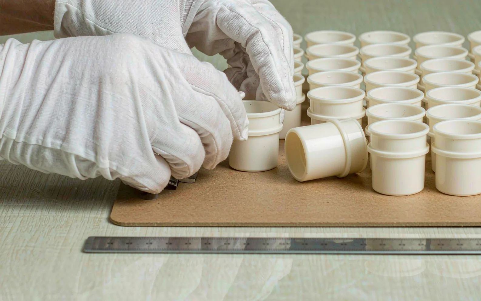 Hands in white gloves checking product dimensions with a tape measure