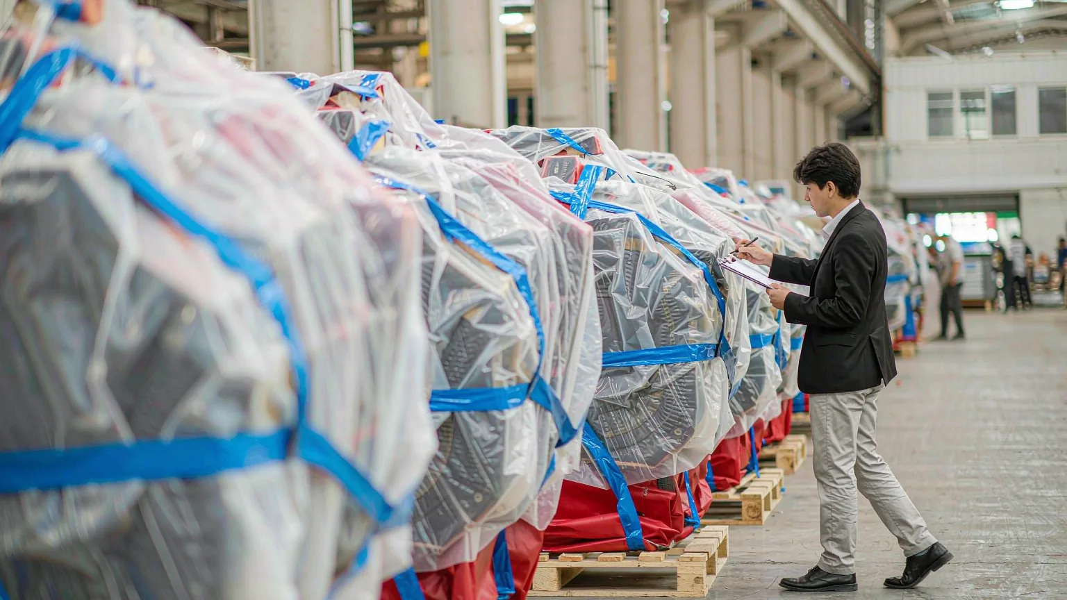 Finished machinery units wrapped and palletised for shipment, checked against the packing list before the balance payment