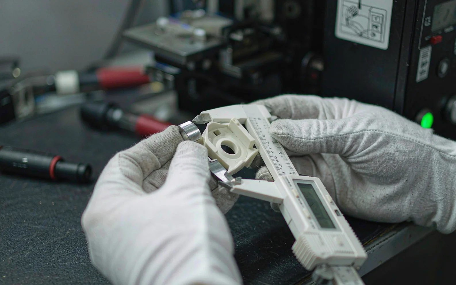 Hands in white gloves inspecting an assembled metal component
