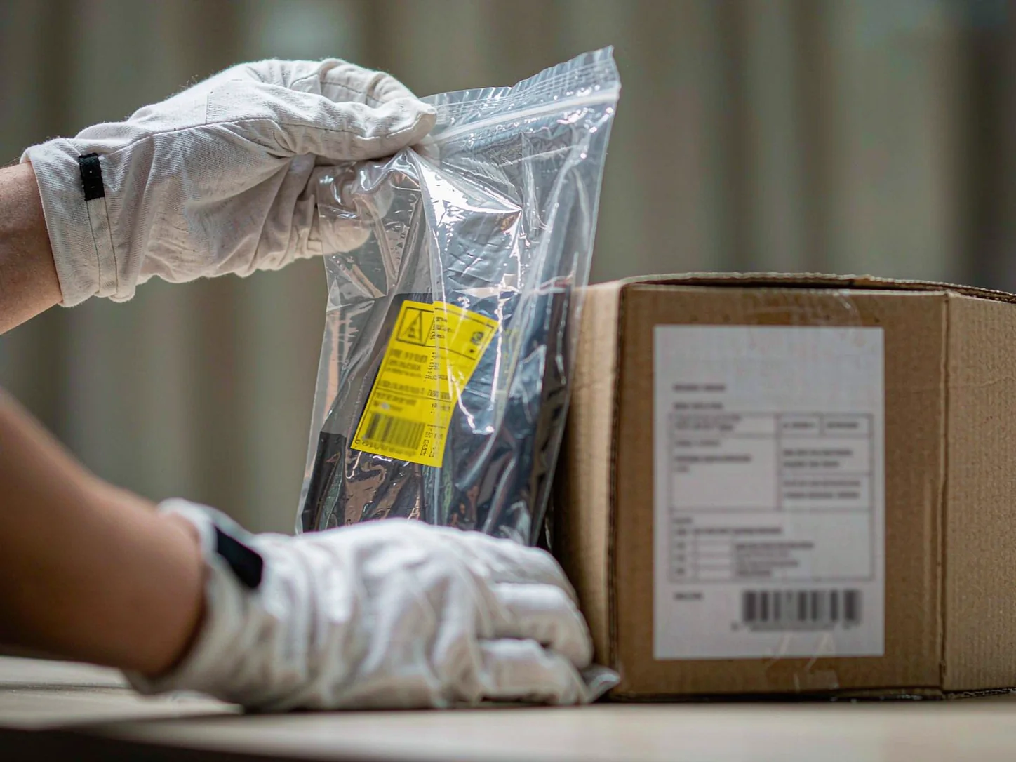 Hands in white gloves checking polybag packing and product labels
