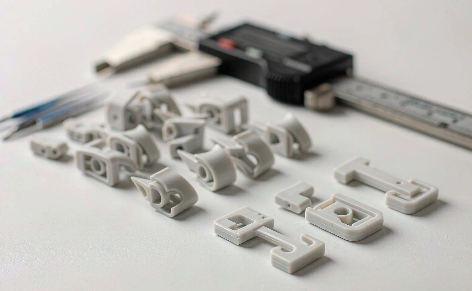 Small molded plastic fittings and clips laid out with calipers for dimensional inspection