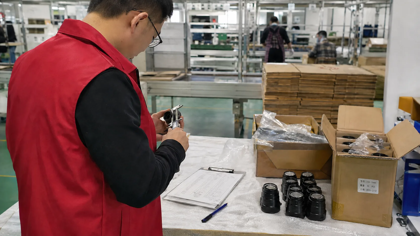 UTS auditor with a clipboard inspecting goods at a factory workbench