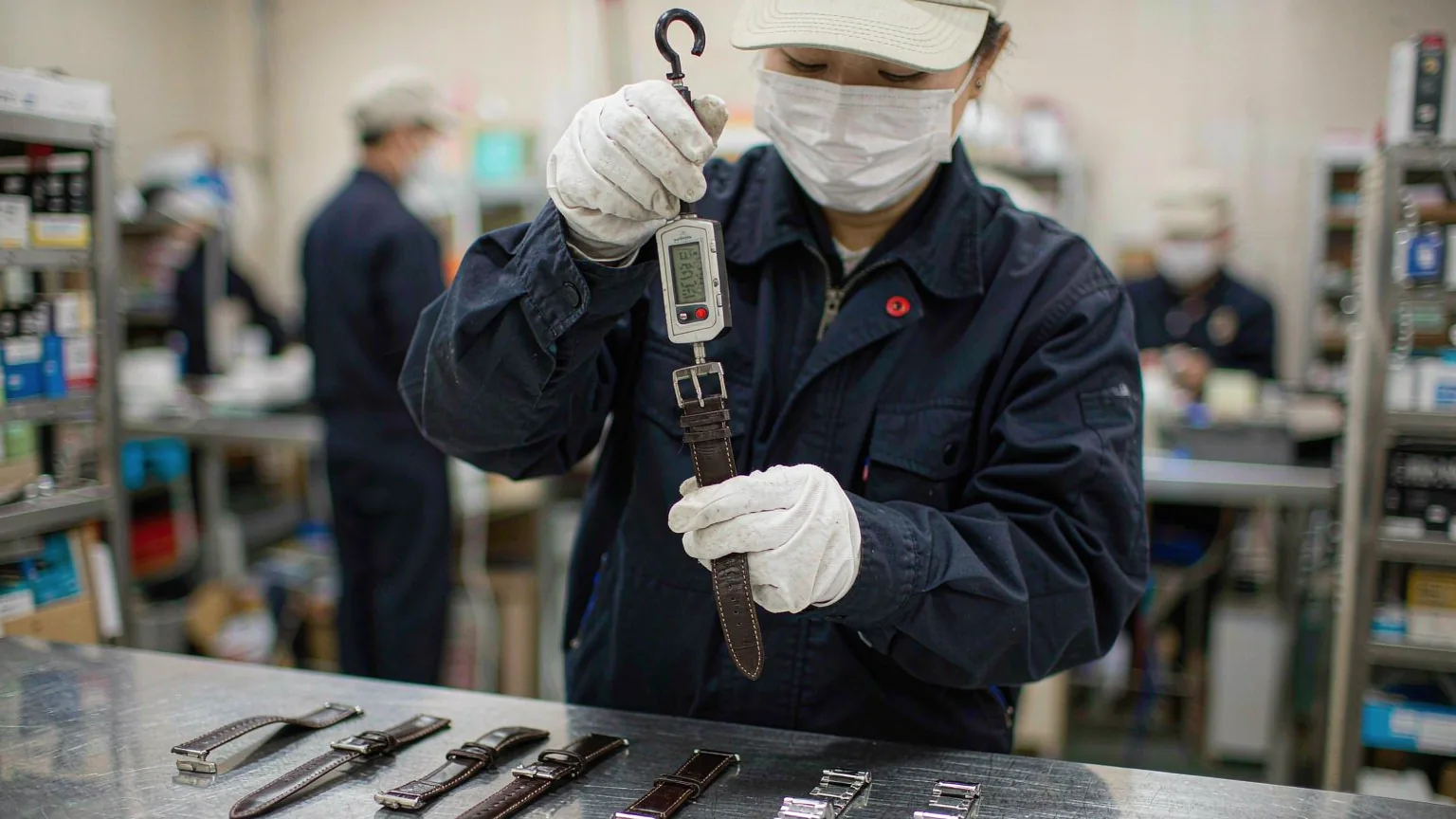 UTS inspector performing a pull test on a leather watch strap and buckle with a digital force gauge